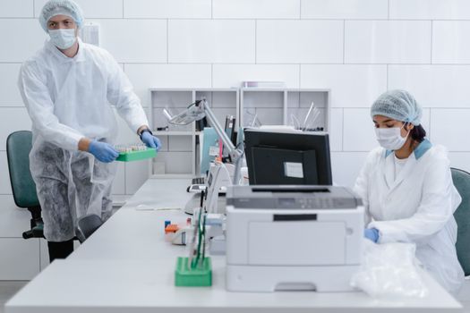 Scientists in protective gear conducting experiments in a modern laboratory setting.