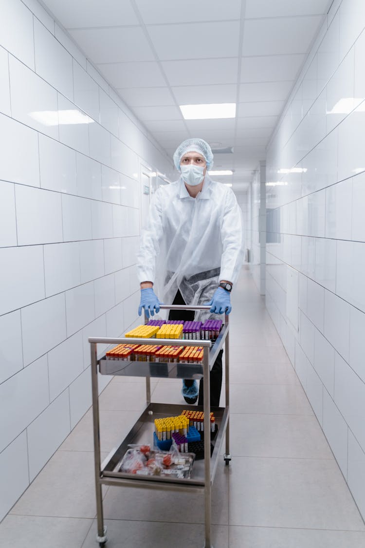 A Man Walking At The Hallway While Pushing A Stainless Cart