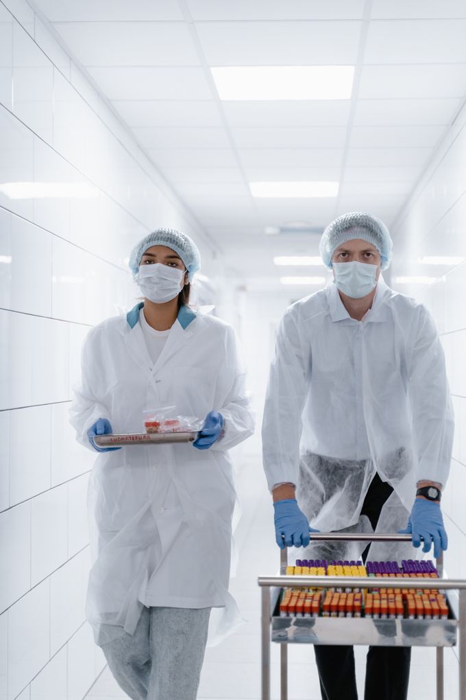 Technicians moving prepared samples through a clean laboratory corridor