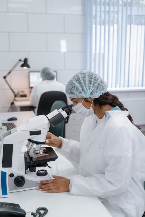 Woman in White Lab Coat Using Looking into Microscope