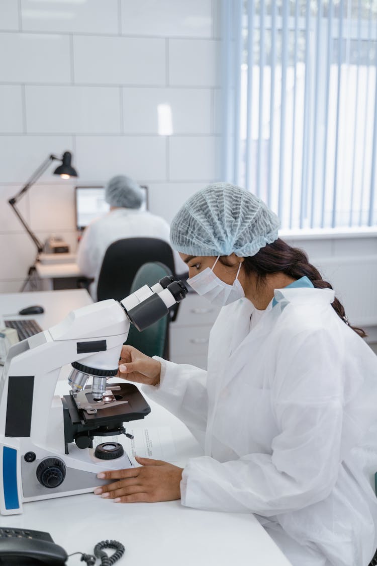 Woman In White Lab Coat Using Looking Into Microscope