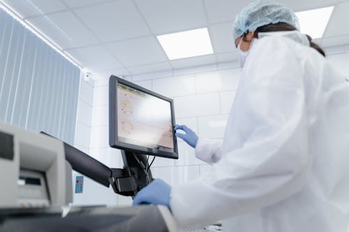 A Woman in White Lab Gown Looking at the Monitor
