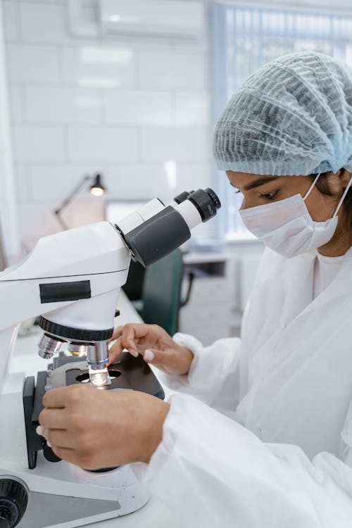Woman in PPE Using a Microscope
