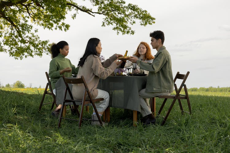 Friends Sitting Around The Table At A Picnic