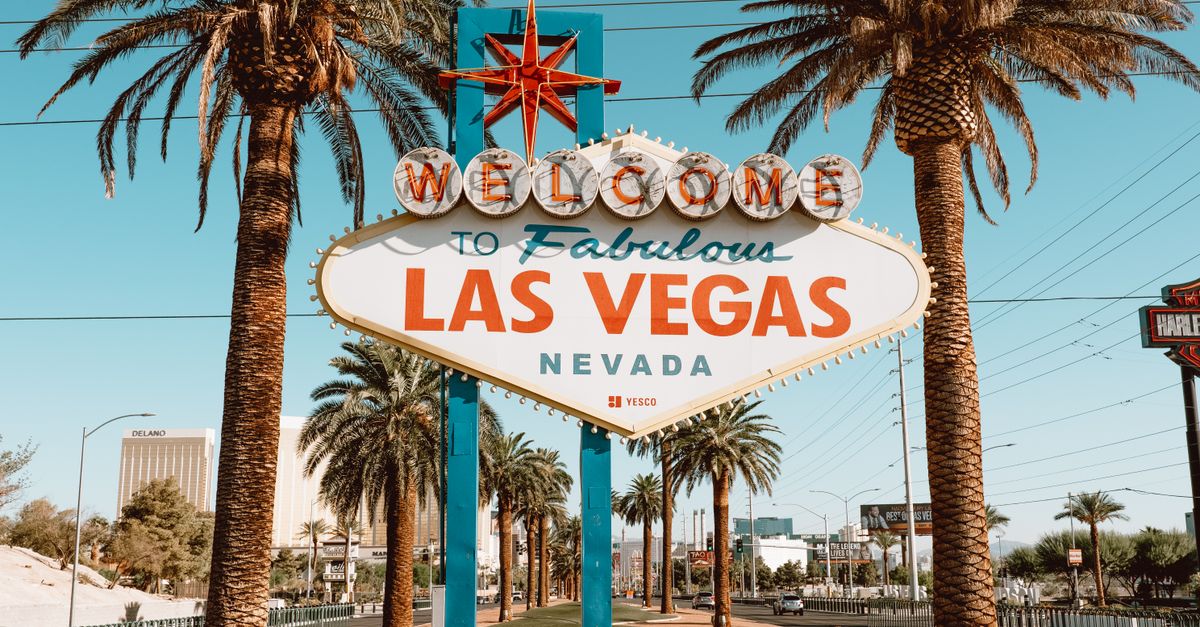 Capture of the famous Welcome to Las Vegas sign surrounded by palm trees under a clear blue sky.