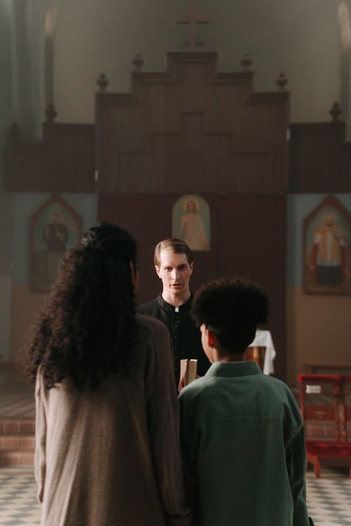 Free A priest speaking to parishioners inside a church, emphasizing community and faith. Stock Photo