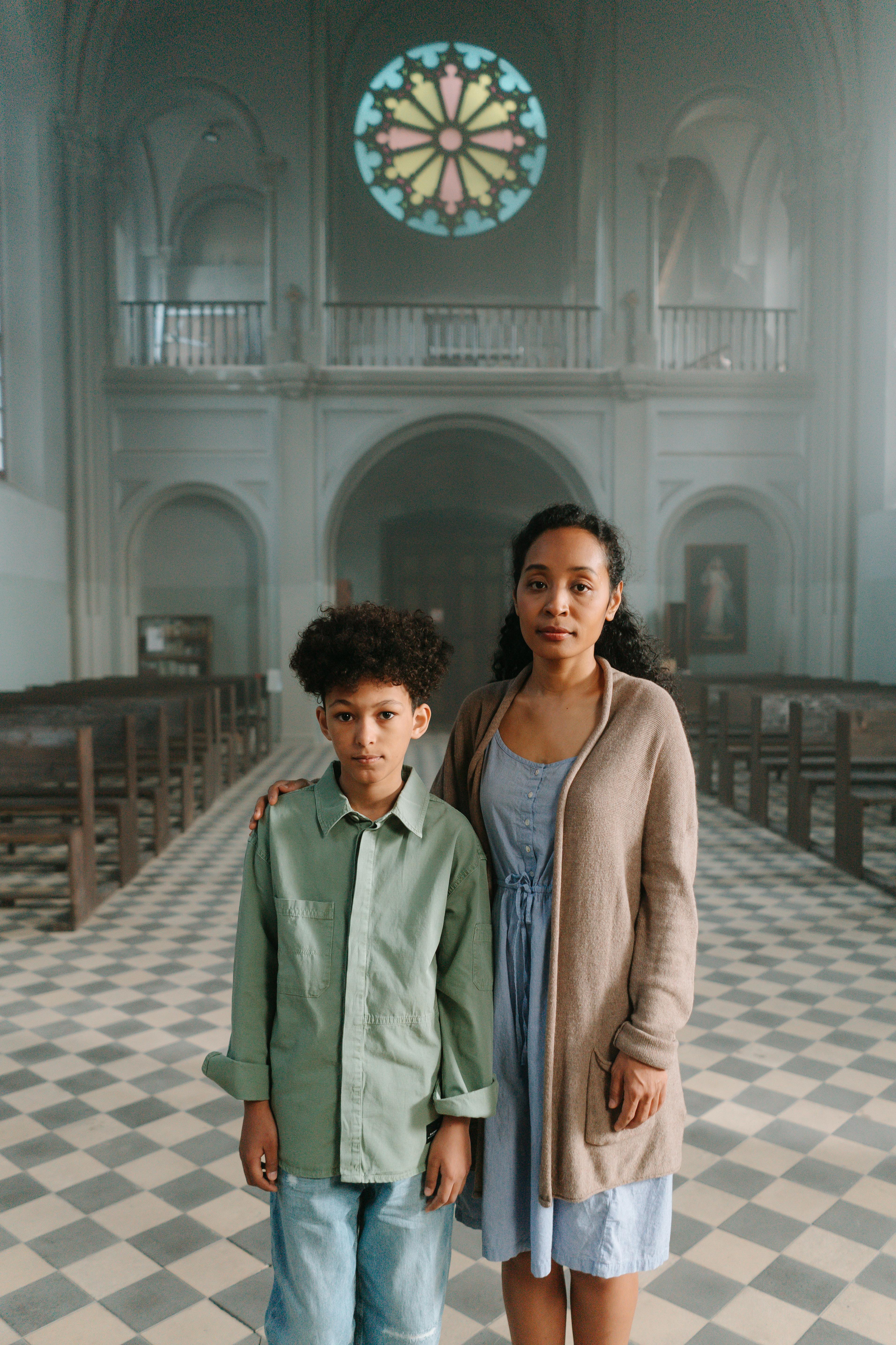 woman in green coat standing on brown brick floor