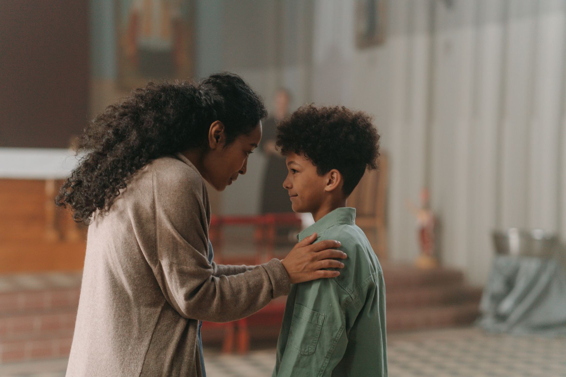 A mother and son share a tender moment inside a church, emphasizing family bond.