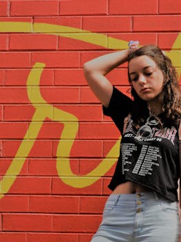 一位时尚的年轻女子在色彩缤纷的涂鸦砖墙前随意摆着姿势