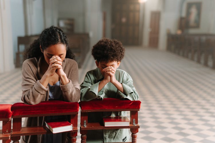 Mother And Son Kneeling In The Church