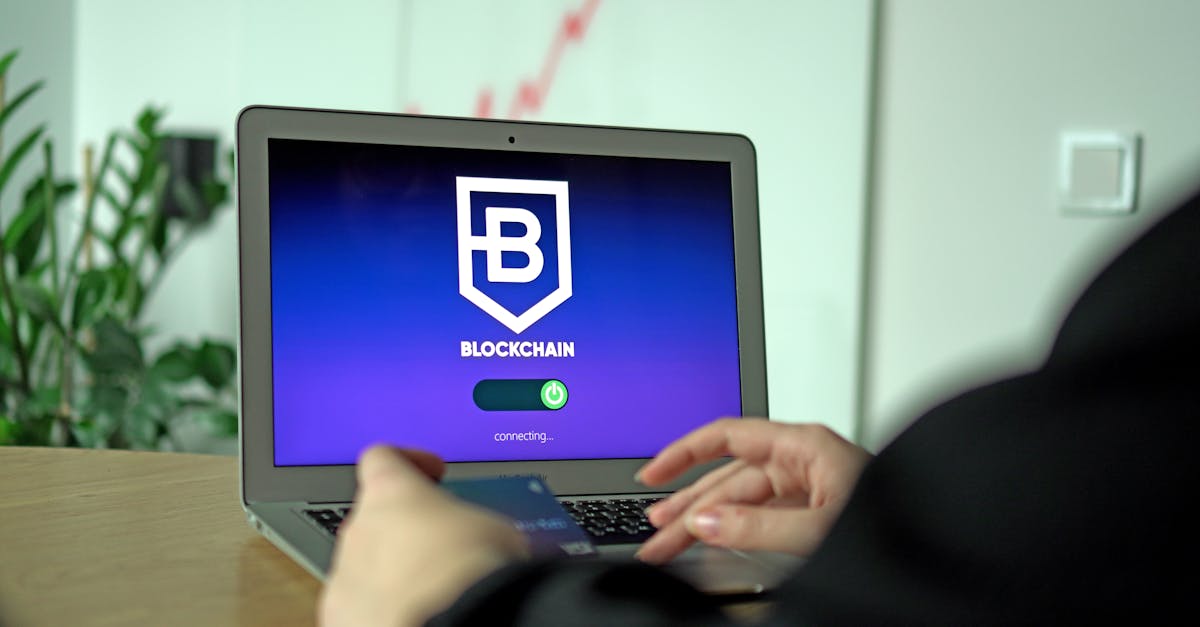 Hand holding a card near a laptop displaying blockchain connection screen.