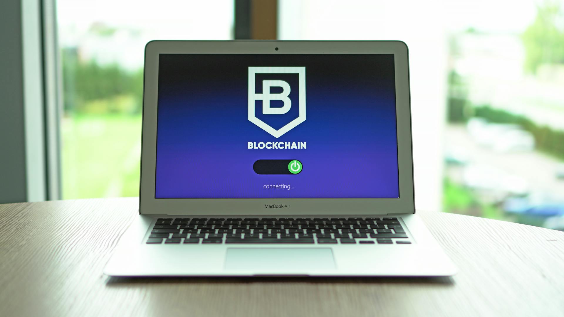 MacBook Air displaying a blockchain concept screen in a bright indoor setting.