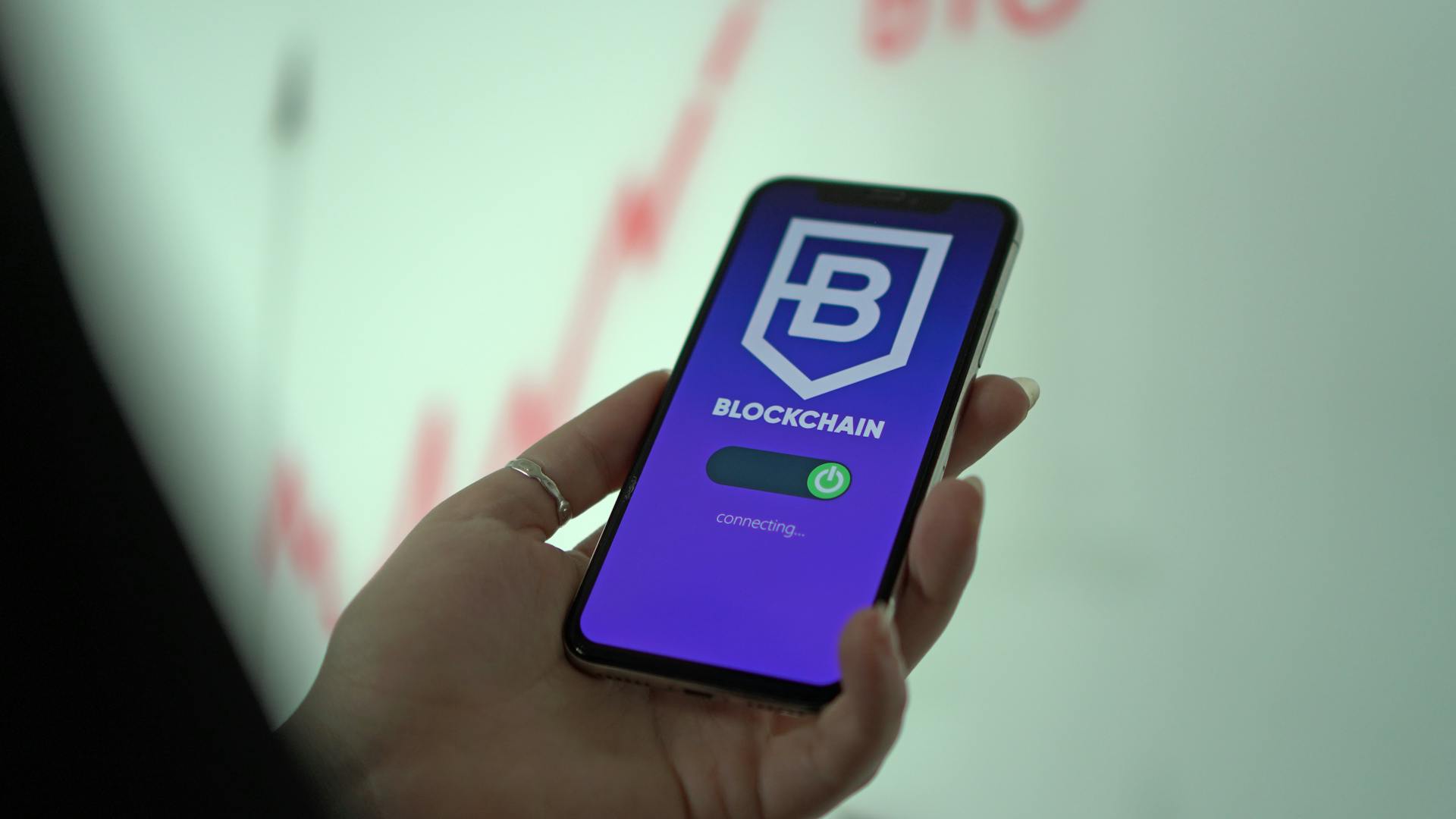 Hand holding smartphone displaying blockchain cryptocurrency wallet.