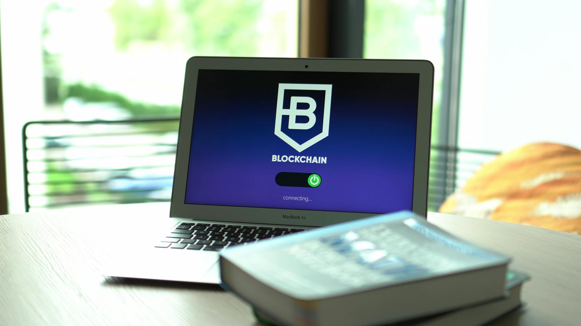 Laptop displaying blockchain connecting screen in modern setting.