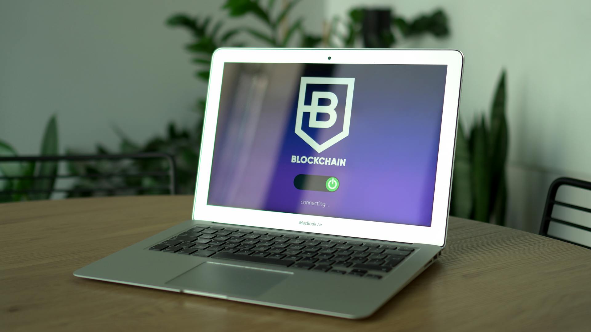 Close-up of a laptop on a table showing a blockchain connecting interface. Modern technology theme.