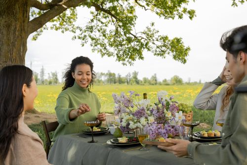 Free A diverse group enjoying a spring picnic with flowers, food, and laughter in a park. Stock Photo