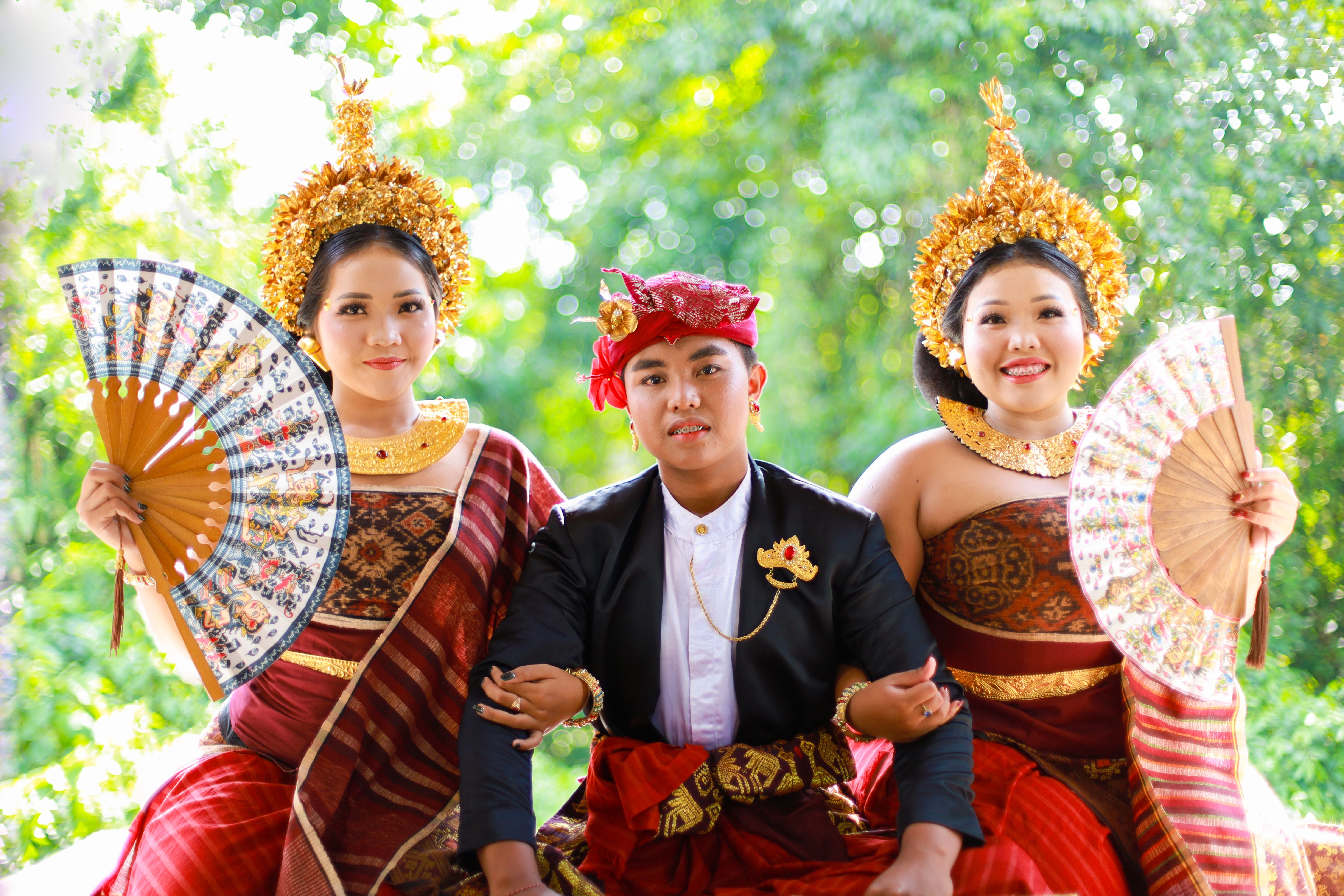 Three young adults in traditional Balinese attire, showcasing vibrant cultural heritage.