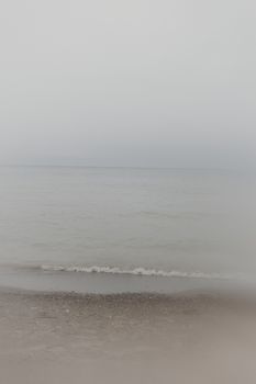 A tranquil beach view with fog, soft waves, and a misty ocean horizon. Ideal for peaceful backgrounds.