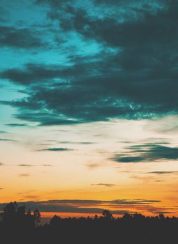 A breathtaking sunset with vibrant colors over a tranquil landscape featuring silhouetted treetops.