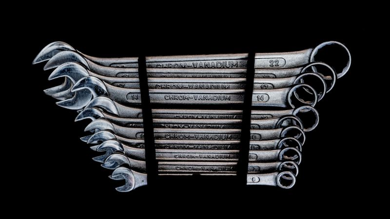 Set of chrome-vanadium wrenches neatly organized on a black background.