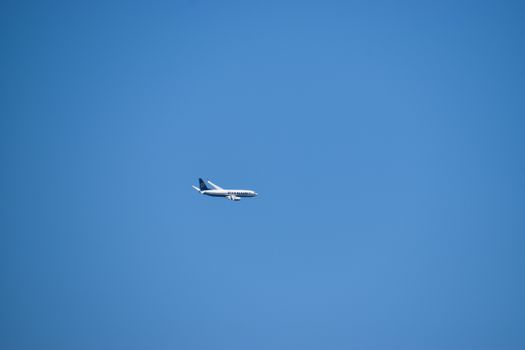 A passenger airplane flying high in a clear blue sky, emphasizing travel and aviation themes.