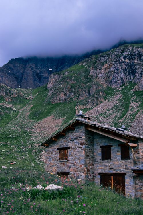 Free Charming stone house nestled in a serene mountainous countryside under cloudy skies. Stock Photo