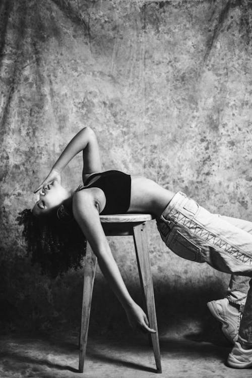 Free Grayscale Photo of a Woman Lying on a Wooden Stool Stock Photo
