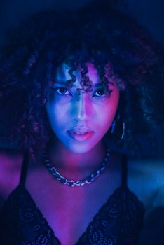 Stunning portrait of young woman with curly hair under vivid neon lighting.