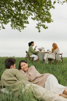 Friends enjoy a serene picnic in a green field, sharing laughter and nature.