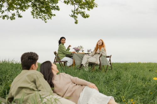 Free A group of friends enjoying a picnic and conversation in a lush green meadow. Stock Photo