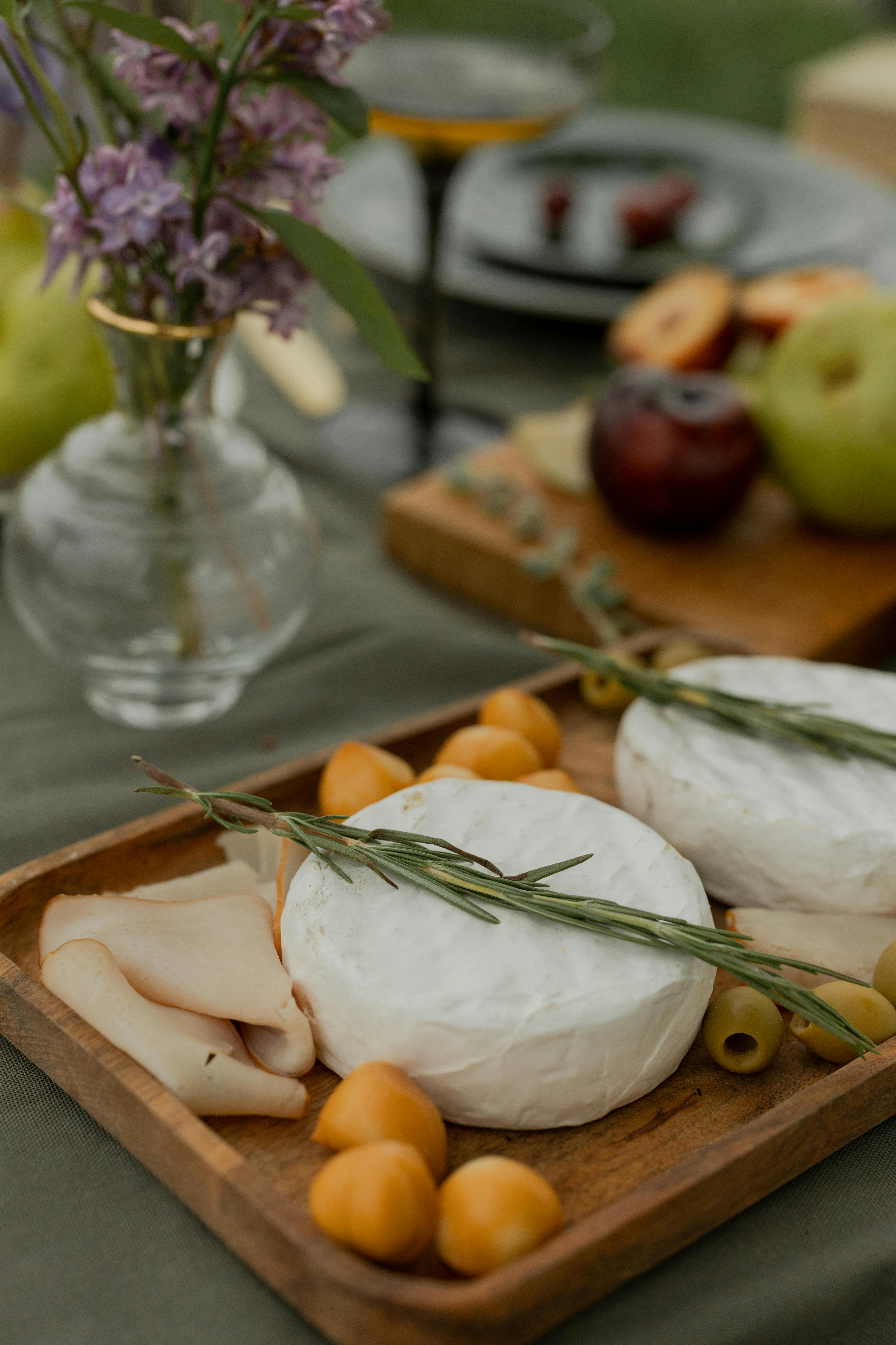 A beautifully arranged cheese board with fruits and flowers, perfect for an outdoor summer picnic.