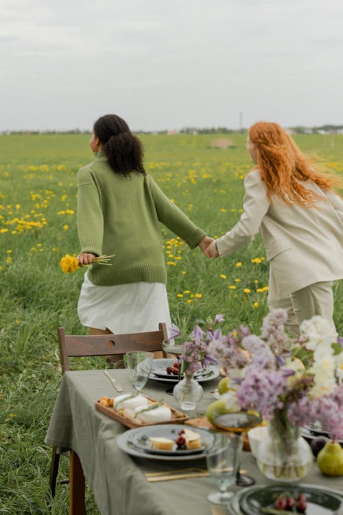 Women Holding Hands while in a Flower Field