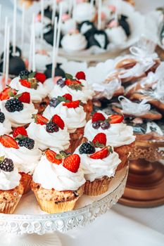 A tempting display of beautifully decorated cupcakes with fresh berries on a stand.