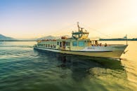 日落时分，贝尔塔客运渡轮穿过奇姆湖，背景是风景优美的山脉