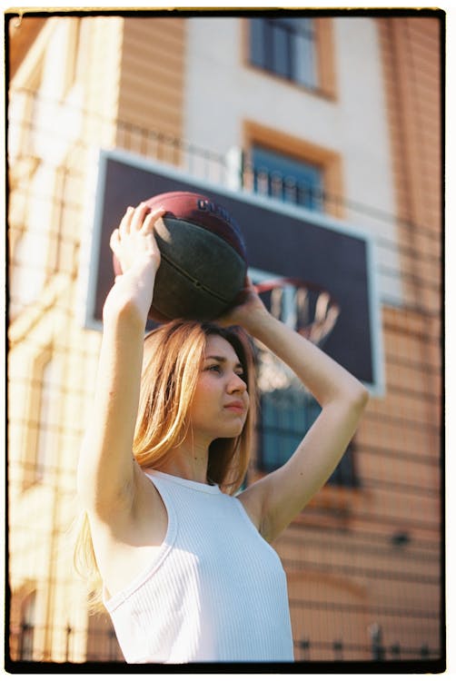 Woman in White Tank Top Holding Black and Red Basketball