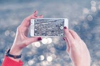 一个女人正用智能手机拍摄鹅卵石的照片