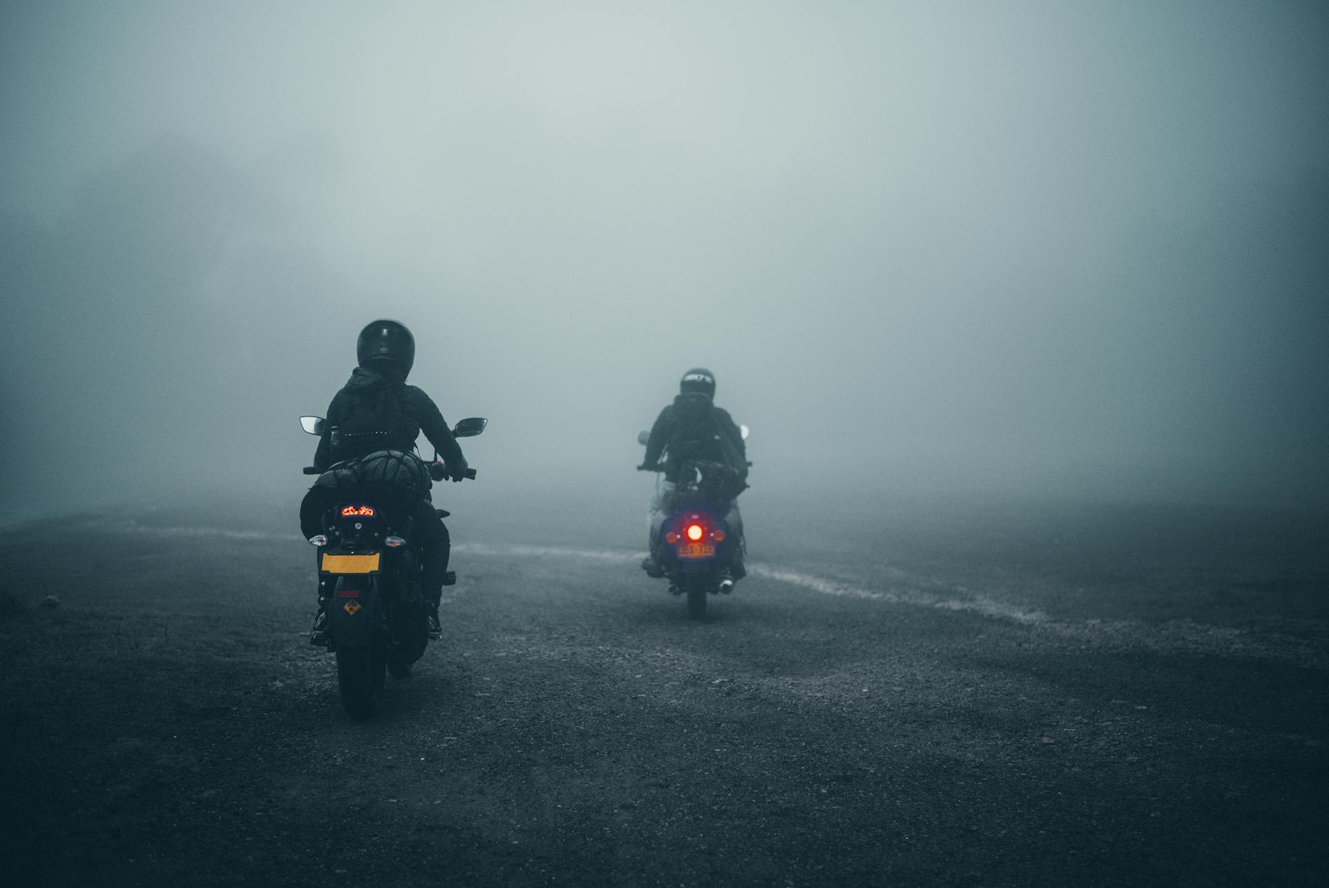 Two motorcyclists ride through a misty road in Soacha, Colombia, creating a moody atmosphere.