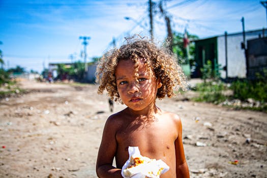 Curly-haired child eating outdoors on a sunny day, embodying innocence and carefree youth.