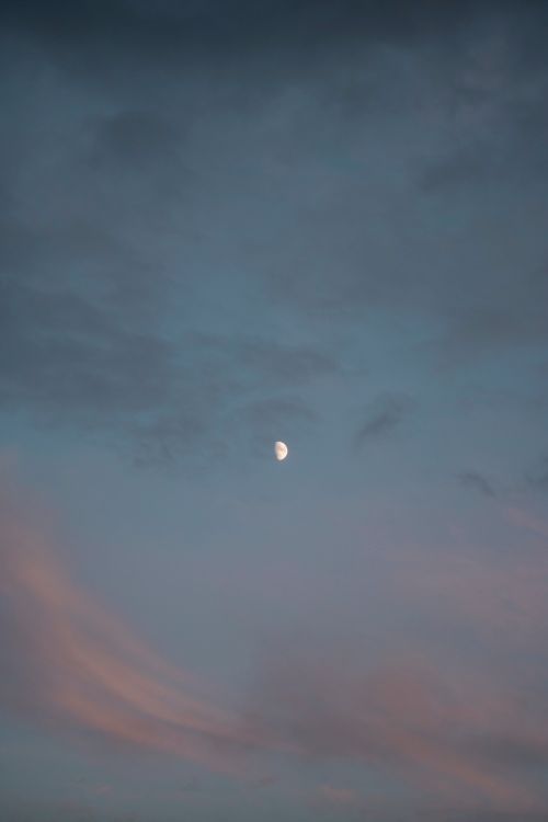 Free A tranquil evening sky featuring a crescent moon amidst colorful clouds. Stock Photo