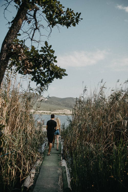 A Man and Woman Walking Between Tall Grass