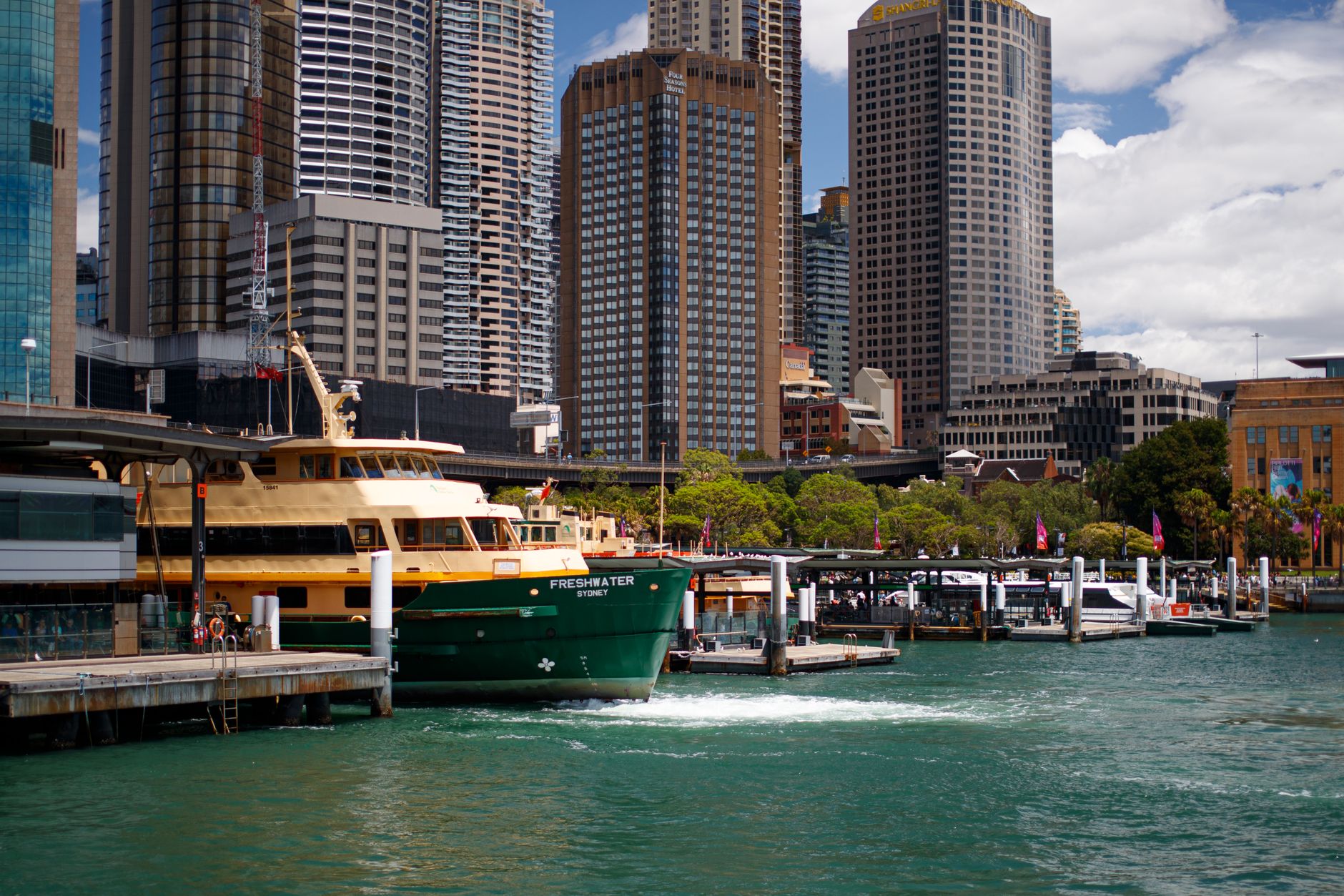A ferry docks at Sydney Harbour with skyscrapers in the background, showcasing urban life.