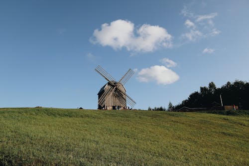 Brown Wooden Windmill on Green Grass Field Under Blue Sky