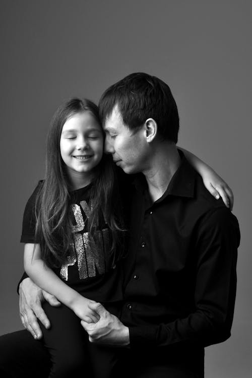 A Grayscale Photo of a Father and Daughter with their Eyes Closed