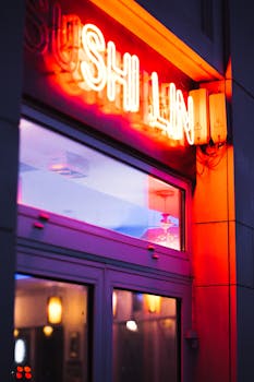 Vibrant neon sign illuminating a restaurant entrance at night with reflections on glass.