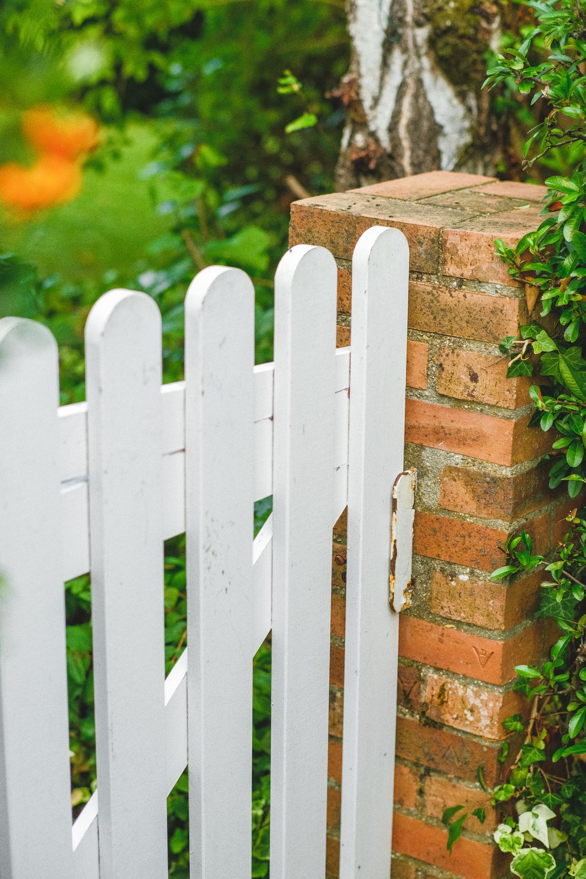White wooden garden gate beside a brick wall