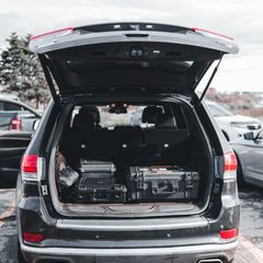 Open boot of a dark SUV with black hard storage cases stacked neatly across the floor