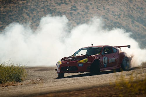 Red Car Releasing Thick Smoke while Moving on the Road