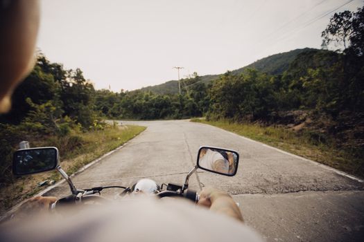 A motorcyclist cruising on a scenic mountain road surrounded by lush greenery.