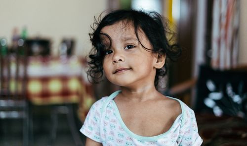 Free Adorable young girl with curly hair and a serious expression indoors. Stock Photo