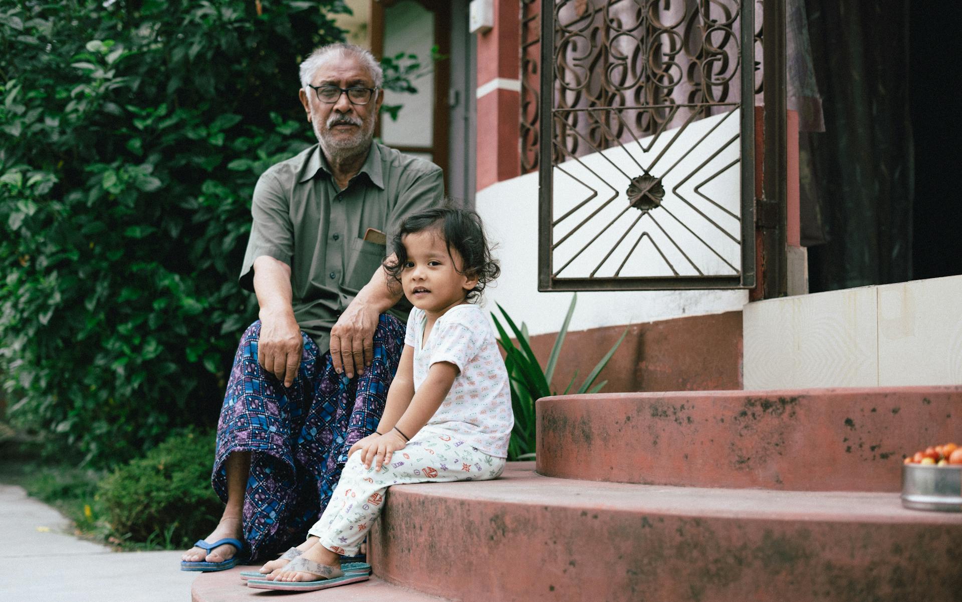 A Grandfather Sitting Together with His Granddaughter Outside Their House